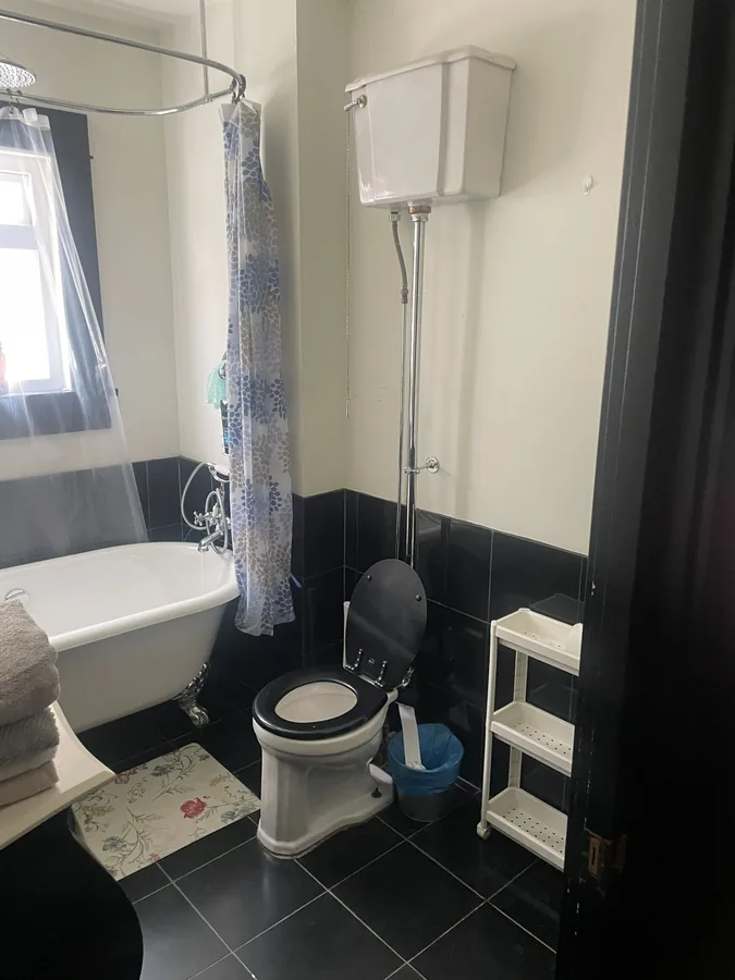 A bathroom with a clawfoot tub and a high tank toilet