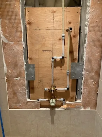 Before: A shower valve roughed in on the open wall, before tiling